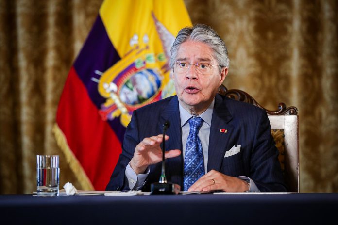 Se ve al Presidente del Ecuador, Guillermo Lasso, emitiendo un discurso en su oficina con la bandera del país por detrás.